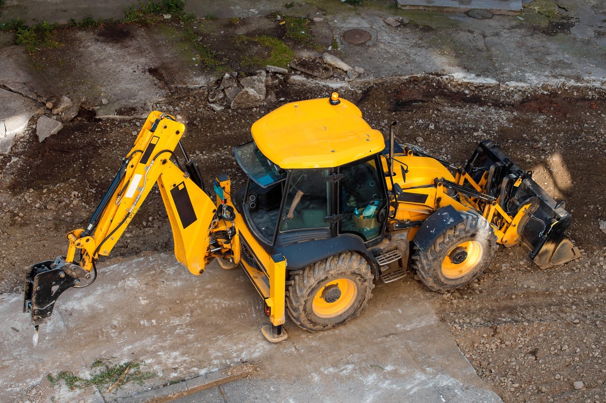 A yellow construction vehicle digging in the ground at a building site